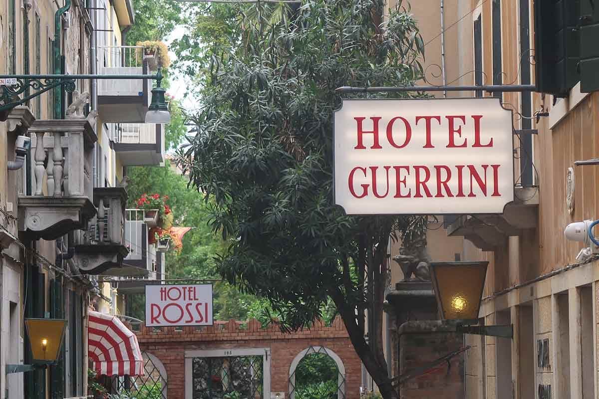 Row of hotels along a Venetian canal with boats moored in front, illustrating typical accommodation in the historic center