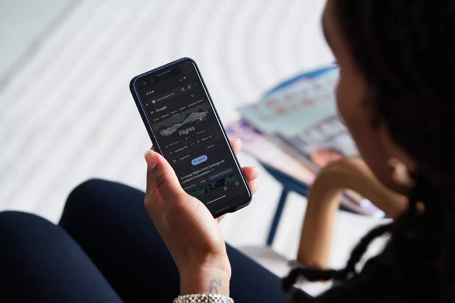 A woman holding a phone with Google Flights
