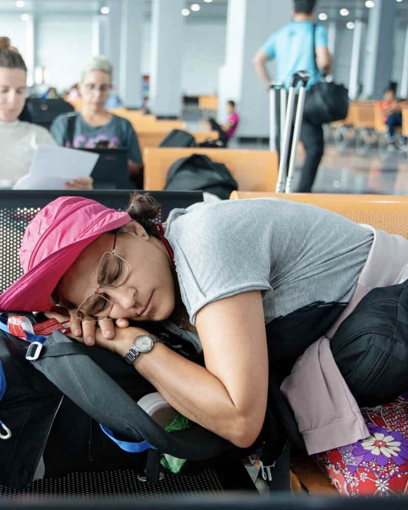 Traveler sleeping on a backpack during a long layover at the airport