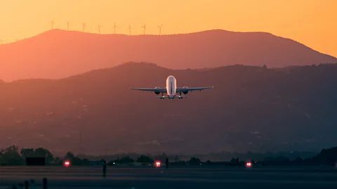 Woman looking at planes on the tarmac, weighing options for a last-minute but budget-conscious trip