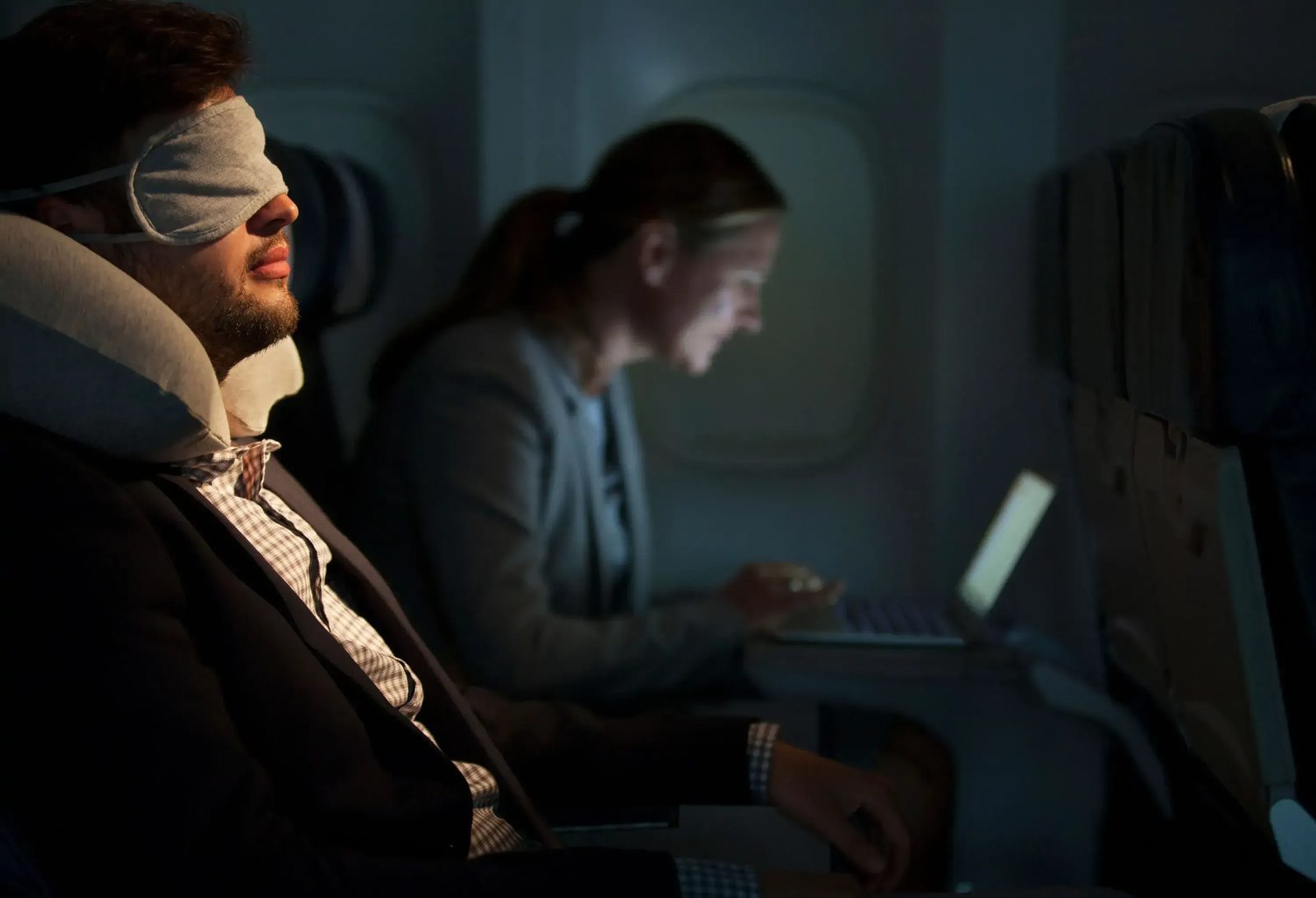 Airplane cabin at night with dimmed lights during a red-eye flight