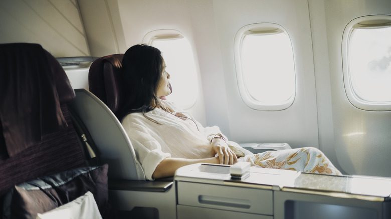 A relaxed business class passenger looking out of an airplane window
