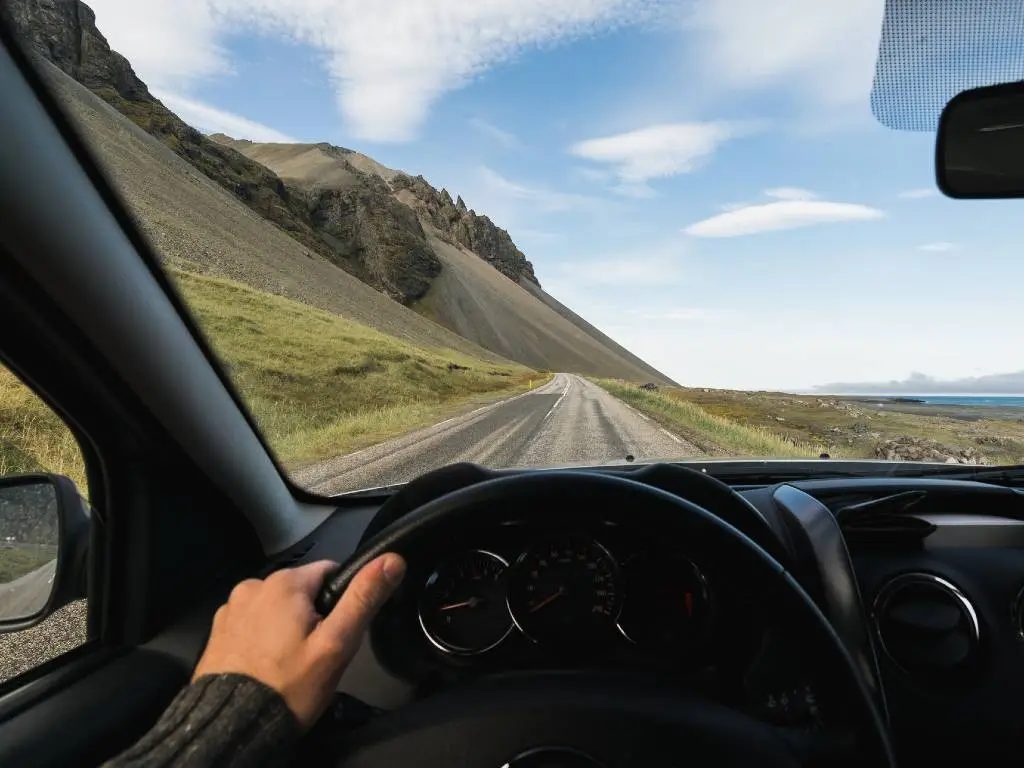 Driving on a scenic road, representing a well-planned budget trip