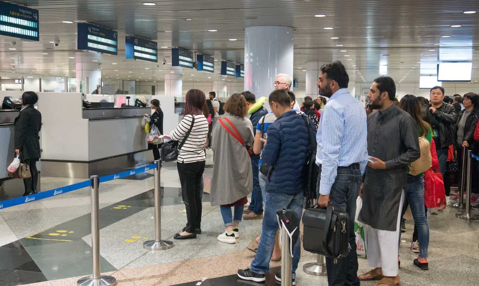 Passengers waiting in line at airport customs and immigration checkpoint