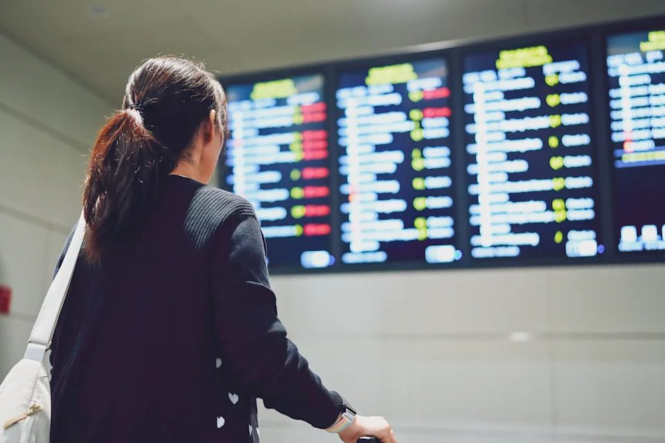 A traveler checking flight information at an airport departure board