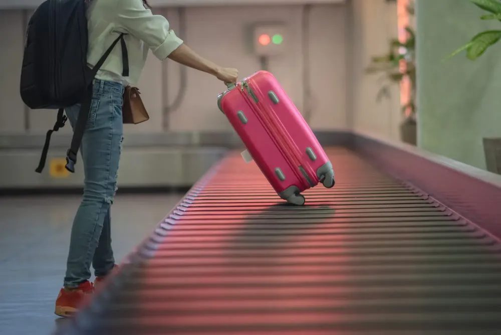 Person collecting the last suitcase from an empty baggage carousel in the airport