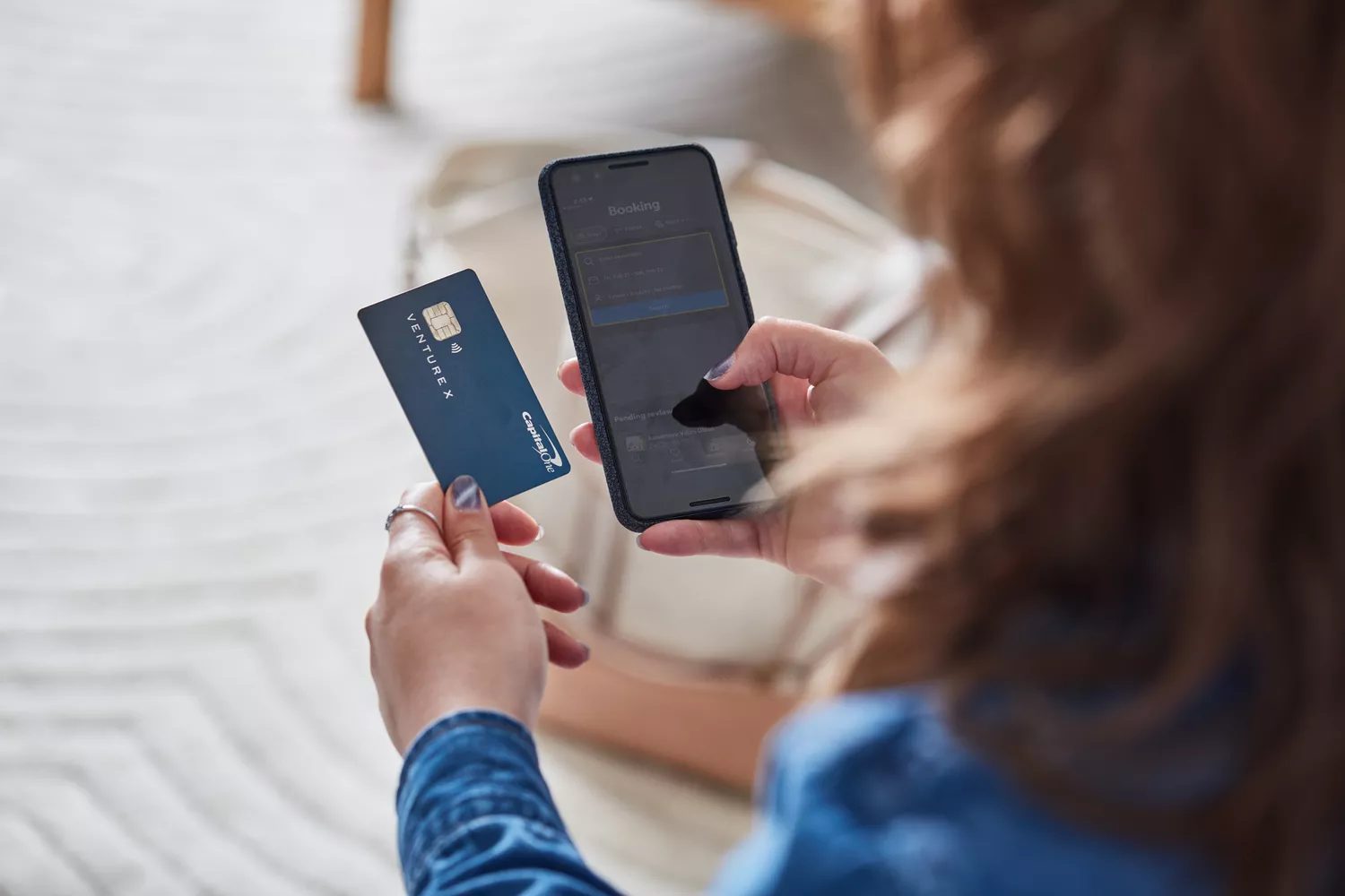 A woman holding a credit card about to book a hotel on a booking app
