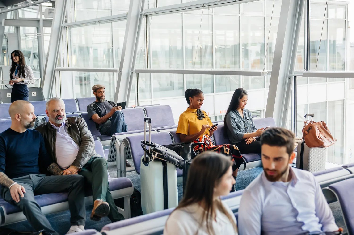 People waiting at an airport gate seated on benches