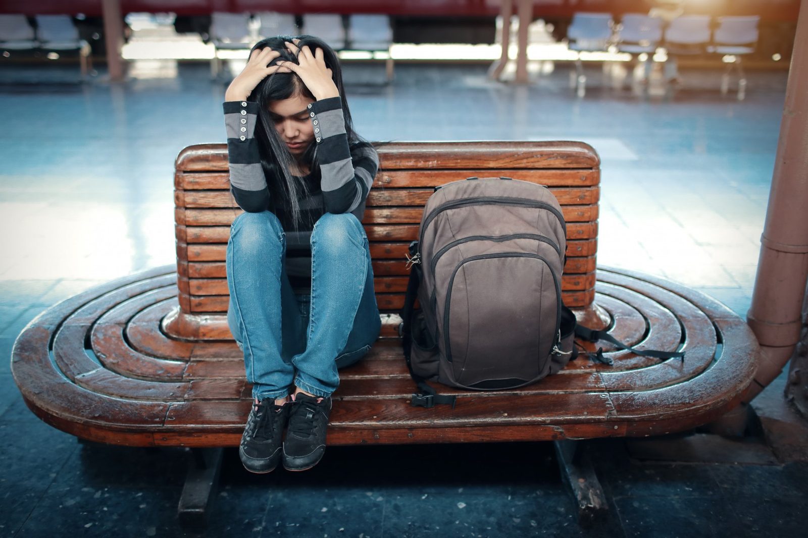 A young woman traveler stressed out sitting on a bench.