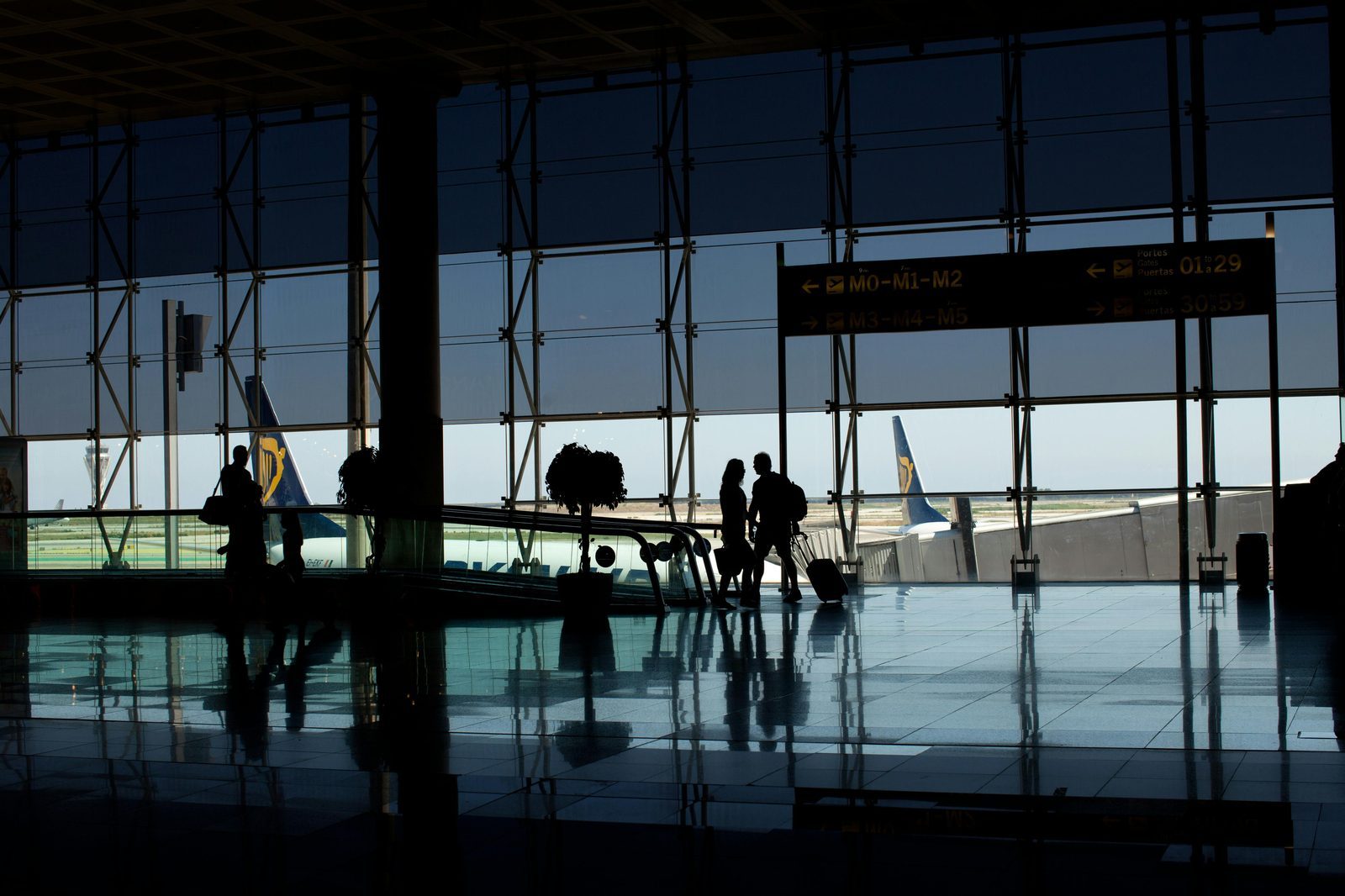 Traveler rolling suitcase at an airport terminal, representing baggage and add-on costs