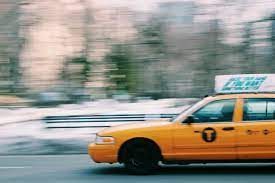 Passenger getting into a taxi outside a busy transport hub at night