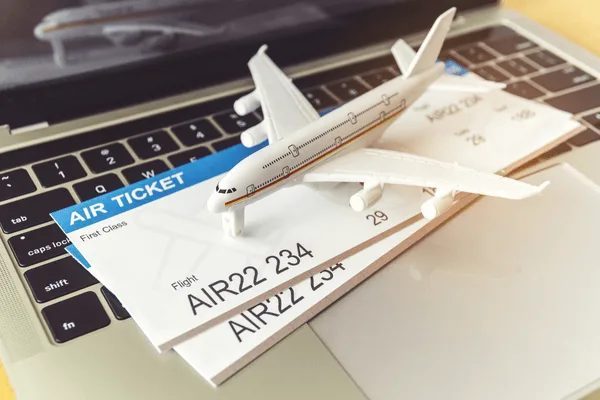 Plane tickets on laptop with toy airplane