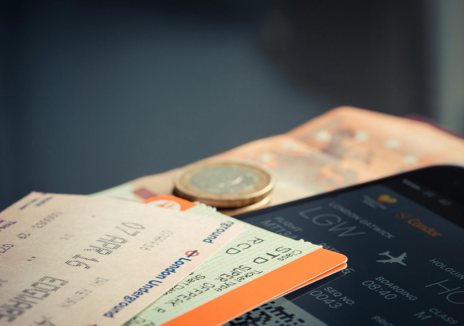 Digital plane ticket on a phone next to cash and transport tickets