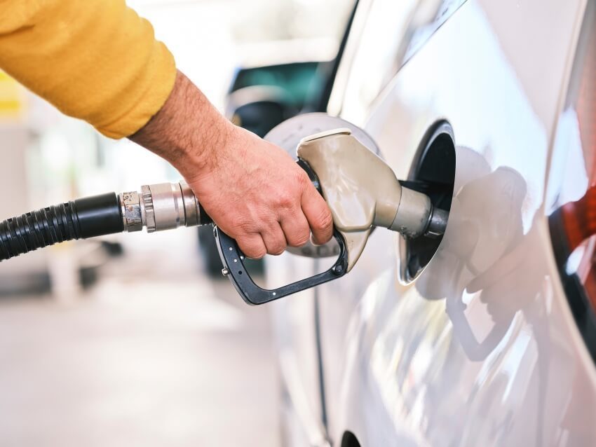 Close-up of a person refueling a car, symbolizing rising fuel costs that affect airfares.