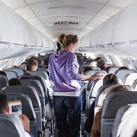 A woman walking down an airplane aisle, representing the modern air travel experience