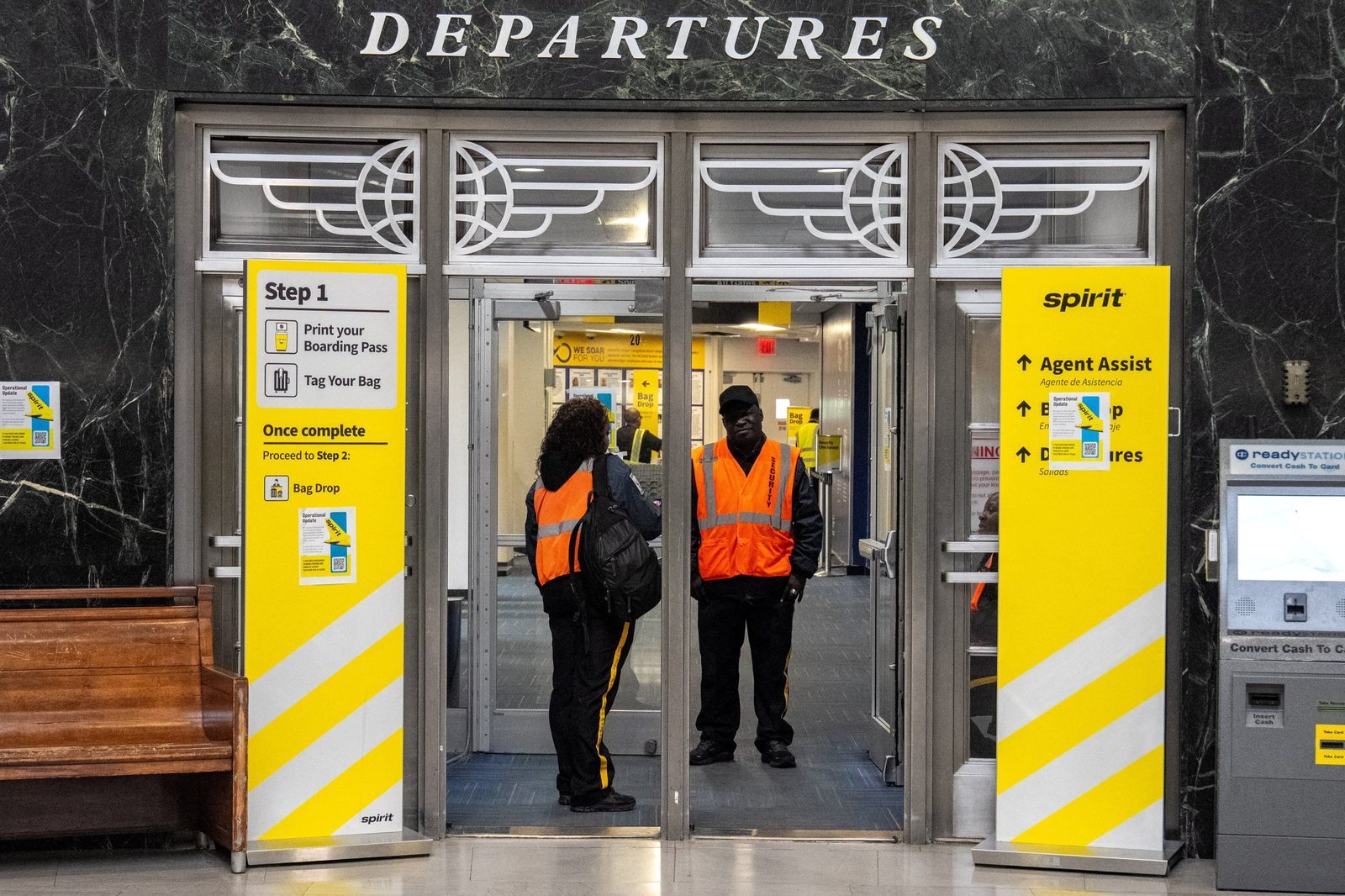 Security guards at a boarding gate with signs informing passengers of the shutdown of Spirit Airlines at LaGuardia Airport