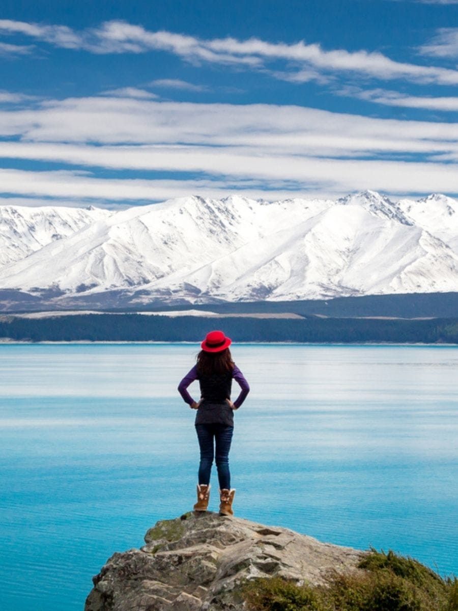 Woman overlooking a lake, reflecting on travel choices