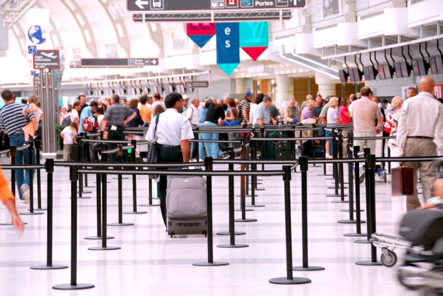 Busy airport filled with people, some checking in, others waiting, all amidst a backdrop of flight information displays.