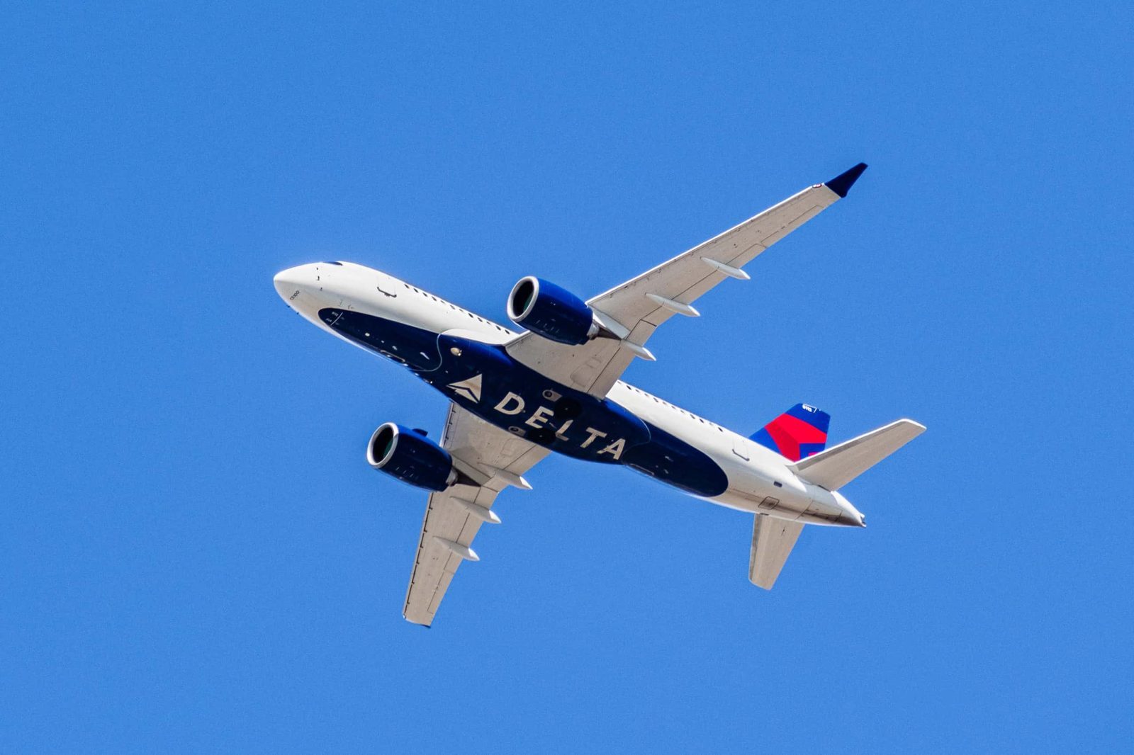 Delta Air Lines aircraft in flight against a clear blue sky, representing frequent flyer and upgrade opportunities