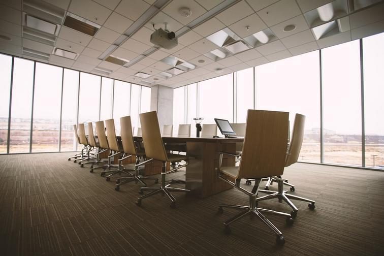 Professionally dressed people collaborating in a modern office setting with laptops and documents.