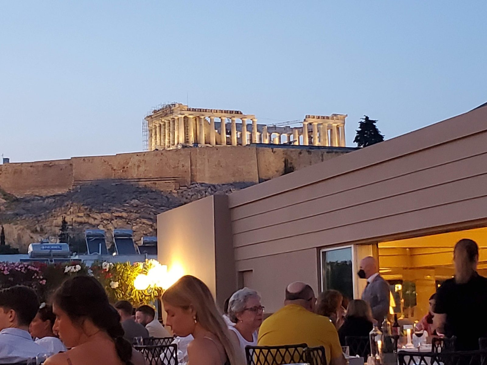 Dinner table in Athens with a view of the Acropolis at night, showing a memorable splurge-worthy meal.