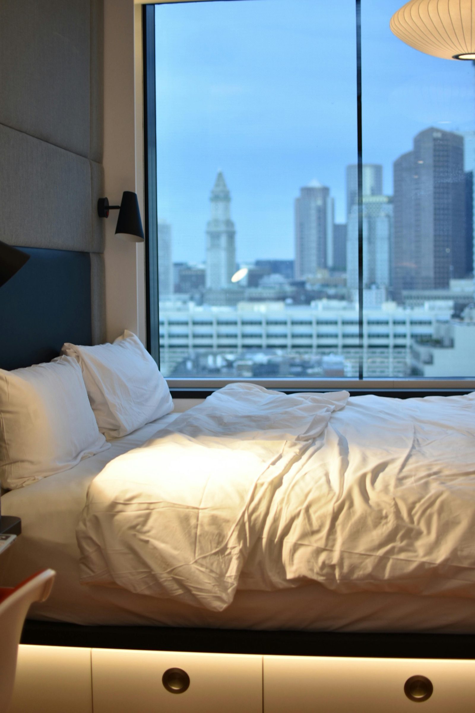 A simple bed in a budget hotel overlooking a city