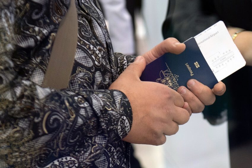 Traveller holding a passport with a plane ticket inside