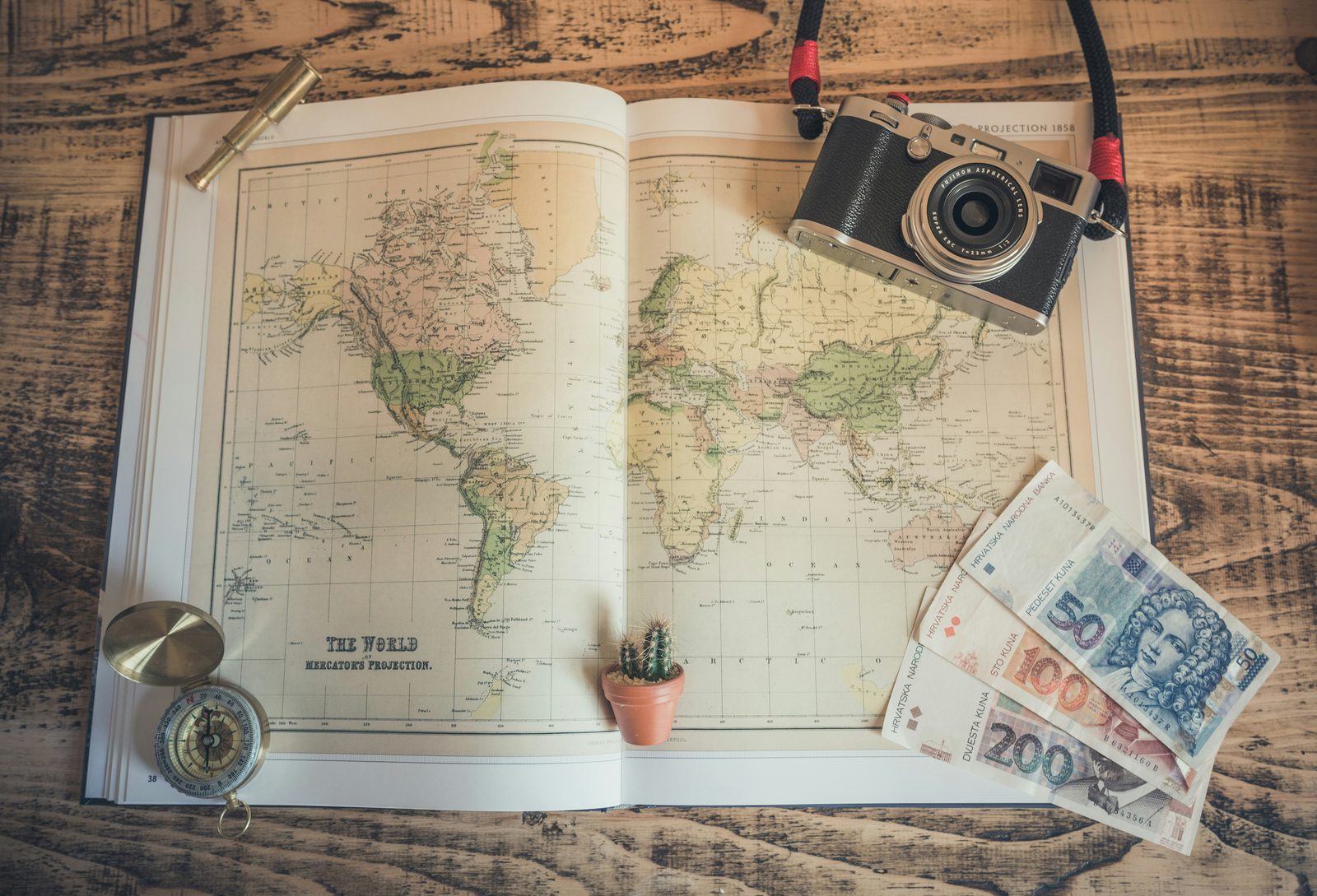 Travel planning items including a camera, map and compass on a table